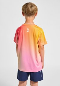 Kortärmad T-shirt med en gradient från orange till rosa, med en mjuk textur och en vit chevron-logotyp på baksidan.