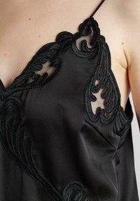 Camisón de satén negro con intrincado bordado negro en el escote, panel sheer delicado y tirantes ajustables.