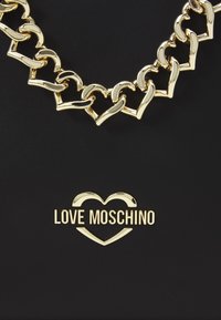 Svart väska med ett guldhjärtformat kedjehandtag och guld "LOVE MOSCHINO"-logotyp. Slät textur med blanka metalldetaljer.