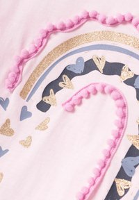 Tela de algodón rosa con un diseño de arcoíris. Acentos dorados, azules y rosas; borde de pompones de felpa; corazones dorados y azules dispersos.