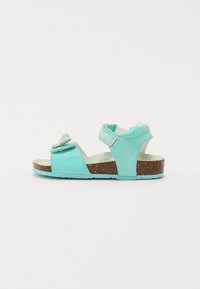 Teal skinnesandal med sommerfugldetalj, to justerbare remmer og korksåle. Glatt tekstur med en skinnende finish.