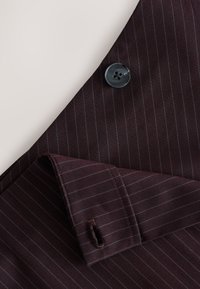 Tissu bordeaux foncé avec de fines rayures discrètes, présentant un col noir à quatre boutons et un col incliné ; texture lisse et coupe sur mesure.