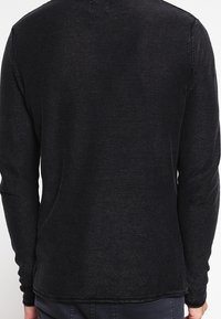 Langärmliger schwarzer Pullover mit strukturiertem Strick, Rundhalsausschnitt und geradem Saum. Schlichtes Design ohne sichtbare Muster oder Verzierungen.