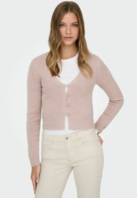 Pink, cropped cardigan with a v-neck, long sleeves, and five front buttons. Soft texture, ribbed hem, layered over a white top.