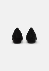 Chaussures à talons en suede noir avec un bout pointu et un petit talon carré. Présente des coutures discrètes le long des coutures et une texture lisse.