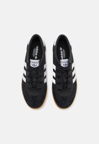 Black suede sneakers with white three-stripe design, rounded toe, and black laces. Gum rubber outsole and perforated mesh detailing.