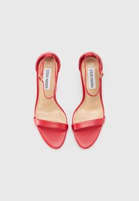 Sandales à talons rouges avec une finition en cuir lisse, une bride à la cheville et une large bride frontale unique. Design ouvert à l'avant et style minimaliste.