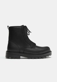 Bottines en cuir noir avec un bout arrondi, une semelle en caoutchouc épaisse, un laçage à l'avant et une texture lisse. Des coutures latérales apportent un détail de design subtil.