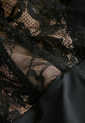 Fekete csipke anyag virágmintákkal, sima fekete selyem alapra varrva, finom részletekkel és texturált megjelenéssel.