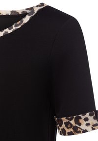 Schwarzes, geripptes Oberteil mit einem Leopardenmuster am Halsausschnitt und umgeschlagenen Ärmeln, das einen Kontrast von Texturen und Mustern bietet.