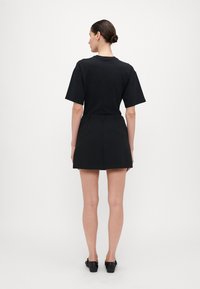 Zwarte short-sleeve t-shirt gecombineerd met een hoge zwarte rok. De outfit heeft een eenvoudig ontwerp en een gladde stoftextuur.