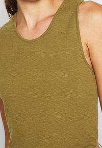 Olivgrünes ärmelloses Oberteil aus geripptem Stoff, mit rundem Ausschnitt und figurbetontem Design. Keine sichtbaren Muster oder Akzente.