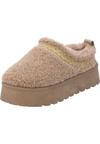 Zapato slip-on beige difuso con parte superior texturizada, detalle de costura amarilla y una suela de plataforma gruesa y marrón claro. Diseño ligero.