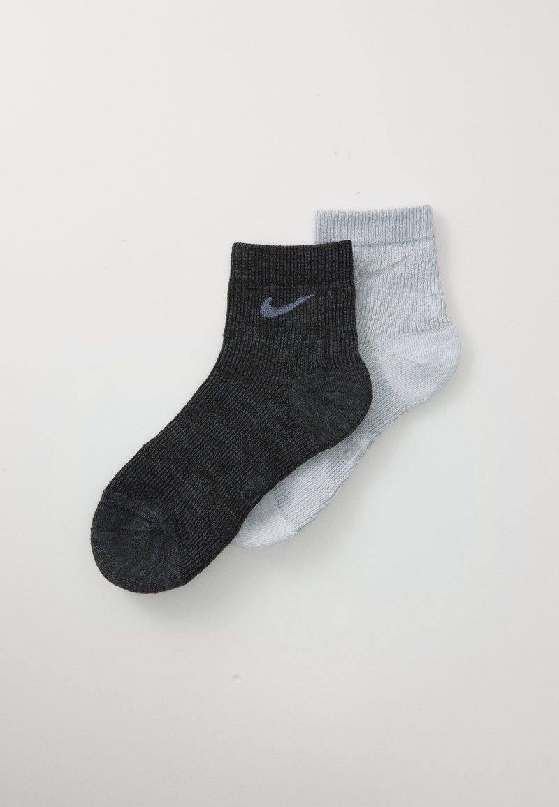 Ein schwarzer und ein hellgrauer Knöchelsocke mit Nike-Swoosh-Logos, übereinandergelegt auf einem weißen Hintergrund.