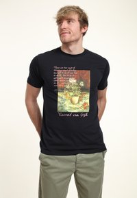 La camiseta de algodón negra presenta una obra de arte impresa de Vincent van Gogh con un jarrón de flores, rodeada de texto en rosa y blanco. Mangas cortas, cuello redondo.