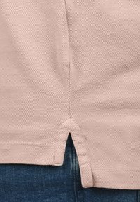 Lichtroze textiel top met een gestructureerde afwerking. Heeft een gespleten zoom en is gecombineerd met blauwe denimstof, wat een casual ontwerp benadrukt.