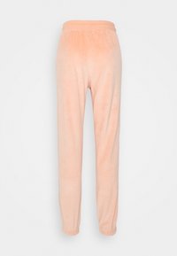 Persikofärgade, mjuka velourbyxor med elastisk midja och smalnande ben. Har rynkade mudd vid anklarna för en snug passform.