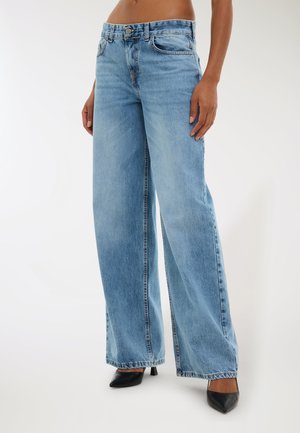 Jeans ampi di colore azzurro realizzati in denim, con chiusura a bottone e cerniera, tasche anteriori e orli sfrangiati. Abbinati a tacchi neri.