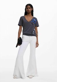 Hall hall v-kaelusega särk, millel on sinine lillemuster, kombineeritud valgete volditud pükstega. Komplekt on mugava lõike ja tekstuurse kangaga.