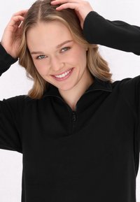 Sort fleece pullover med halv-zip krave, der har en blød tekstur og en afslappet pasform.  Ærmekanterne strækker sig let over håndleddene.