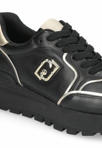Sneaker nera in pelle con una finitura testurizzata, dettagli in argento e un logo prominente sul lato. Presenta una suola spessa e scanalata.