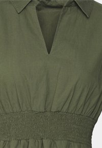 Abito verde oliva con colletto, scollatura a V e vita arricciata. Realizzato in tessuto testurizzato con una silhouette rilassata.