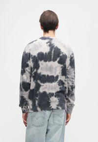 Sweatshirt em tie-dye cinza e preto com mangas longas e decote redondo, feito de um tecido suave, apresentando um corte descontraído e punhos canelados.