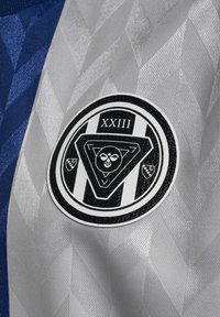 Grå og marineblå sportsjersey med et struktureret diamantmønster, med et cirkulært sort og hvidt logo, der viser teksten "XXIII" og geometriske former.