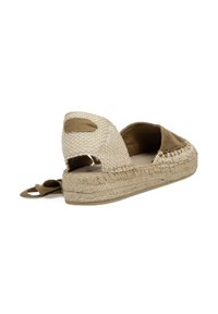 Zapato espadrille de tela beiga tejida con interior de ante marrón, parte trasera abierta, suela de yute y un pequeño lazo de tela para facilitar su uso.