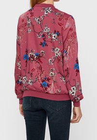 Veste bomber fleurie en tissu bordeaux ornée de fleurs bleues et blanches, avec poignets et ourlet côtelés, et une coupe décontractée.