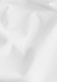Vitt bomullstyg med en slät textur och lätt skrynklighet, som visar en mjuk yta och jämn färg över hela.