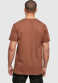 Brown short-sleeve T-shirt made of cotton with a crew neckline, featuring a simple back design and a relaxed fit.
