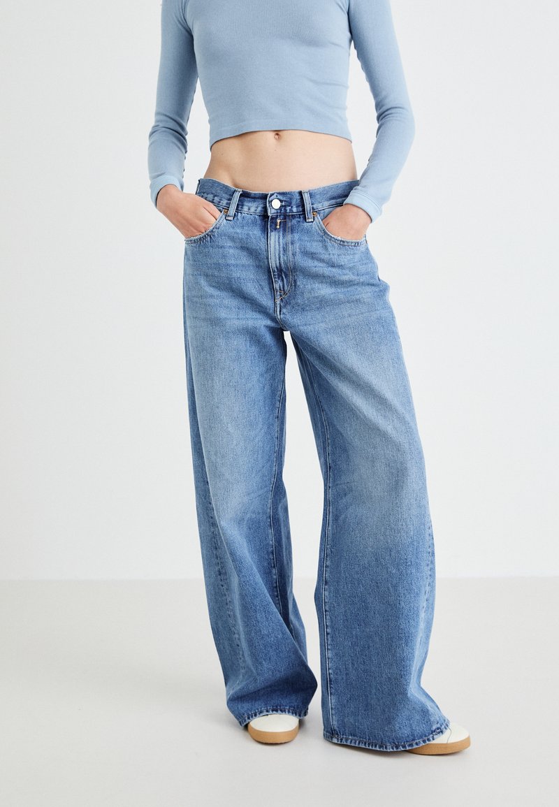 Light blue crop top paired with wide-leg, light-wash denim jeans. The jeans feature a classic five-pocket design and visible stitching.