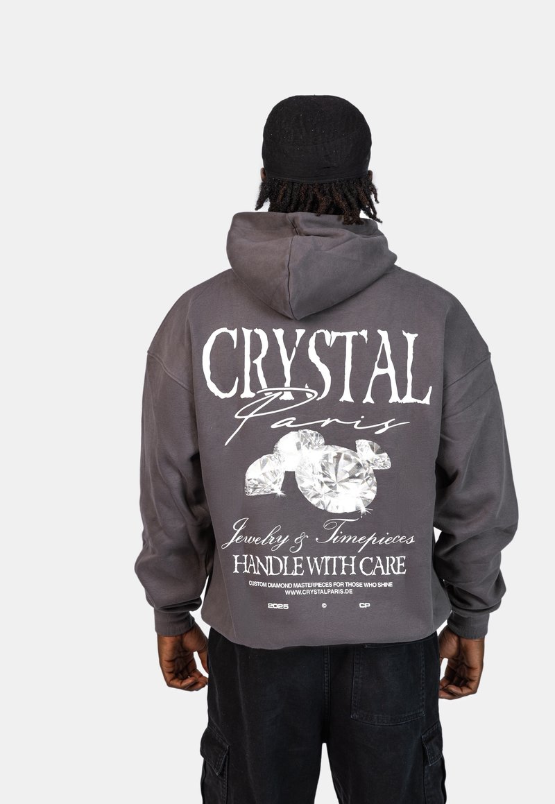 Szara, krótka bluza z kapturem z dużym białym nadrukiem z tyłu, który zawiera tekst "CRYSTAL Paris" oraz grafiki diamentów.