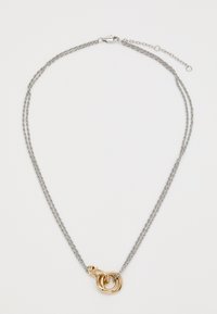 Collana doppia in argento con un pendente circolare intrecciato in oro e un chiusura regolabile su uno sfondo bianco.