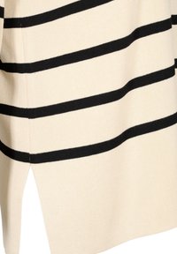 Tissu couleur crème avec des rayures noires horizontales et une fente latérale sur un vêtement en maille.