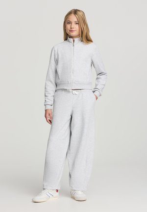 Felpa corta grigio chiaro con zip frontale e polsini a coste, abbinata a pantaloni da jogging a gamba larga coordinati con vita a coulisse.