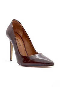 Bordeaux gepatenteerd leren hoge hak pump met een spitse neus, voorzien van een beige binnenvoering en een slanke, metallic gouden stiletto hak.