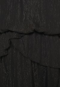 Schwarzer Kleidungsstoff mit einer weichen, strukturierten Oberfläche, der Rüschenschichten und subtile metallische Fäden für zusätzliche Details aufweist.