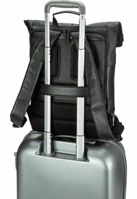 Zwarte stoffen rugzak met gewatteerde banden, gemonteerd op een zilveren harde koffer met een uitschuifbare handgreep en een gestructureerd oppervlak.