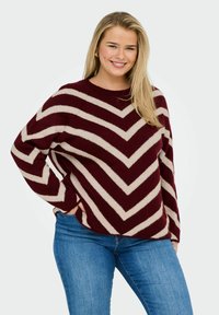 Maglione a righe bordeaux e crema con un motivo a zigzag, scollatura rotonda e vestibilità rilassata. Il materiale sembra morbido e sostenuto.