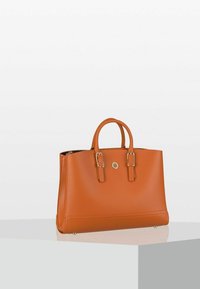 Borsa a mano in pelle tan con due manici corti, dettagli in metallo dorato e superficie liscia. Presenta un logo centrale e un design strutturato.