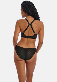 Ensemble de lingerie noire comprenant un soutien-gorge bralette à dos nageur avec bretelles ajustables et un bas à taille basse assorti, tous deux en tissu doux et texturé.