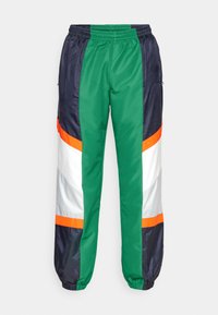 Kleurige trackpants met groene, marineblauwe, witte en oranje panelen. Gemaakt van gladde, glanzende stof met een elastische tailleband en bijgetailleerde hemden.