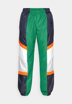 Bunte Trainingshosen mit grünen, navyblauen, weißen und orangefarbenen Paneelen. Hergestellt aus glattem, glänzendem Stoff mit einem elastischen Bund und Bündchen am Saum.