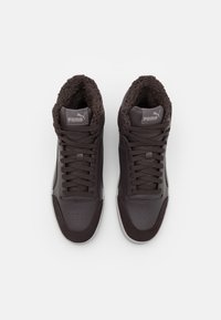 Wysokie sneakersy z ciemnobrązowej skóry i futrzanym wykończeniem. Cechy to płaskie sznurówki, perforowany czubek oraz logo Pumy na języku.