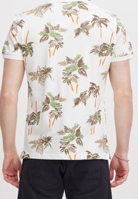 Korte mouwen shirt van witte stof met een tropische palmenbladprint in groene, bruine en oranje tinten. Zachte textuur met een ontspannen pasvorm.