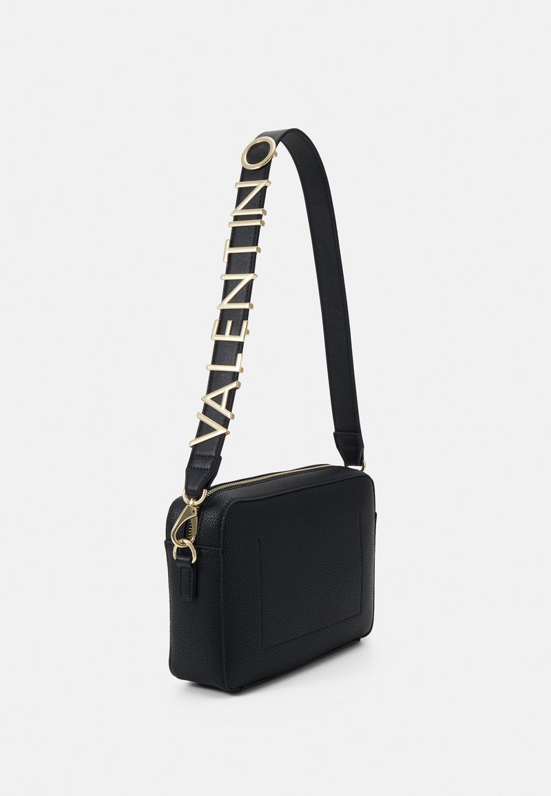 Schwarze Leder-Crossbody-Tasche mit strukturierten Oberflächen, Reißverschluss und einem Schultergurt mit goldener Schrift und Akzenten.