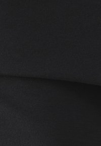 Zwarte stof met een gladde textuur, die overlappende lagen toont. Het materiaal lijkt zacht en rekbaar, geschikt voor aansluitende kleding.