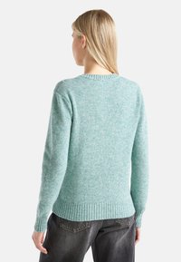 Jasnoniebieski sweter wykonany z teksturowanej dzianiny, z okrągłym dekoltem, długimi rękawami oraz ściągaczami przy mankietach i u dołu.